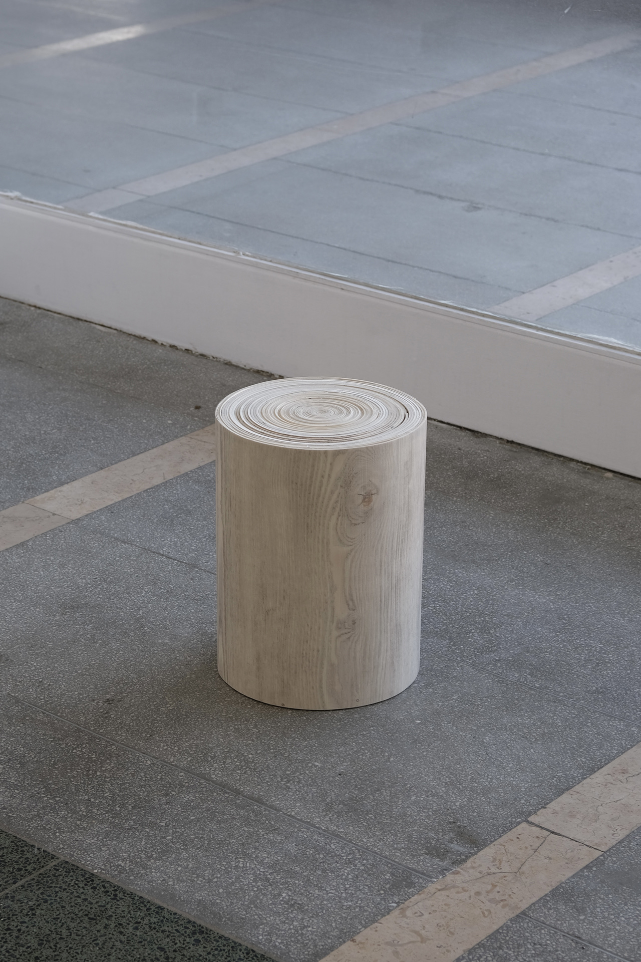 image of a wood effect vinyl flooring sheet rolled into the sizes of a stool chair