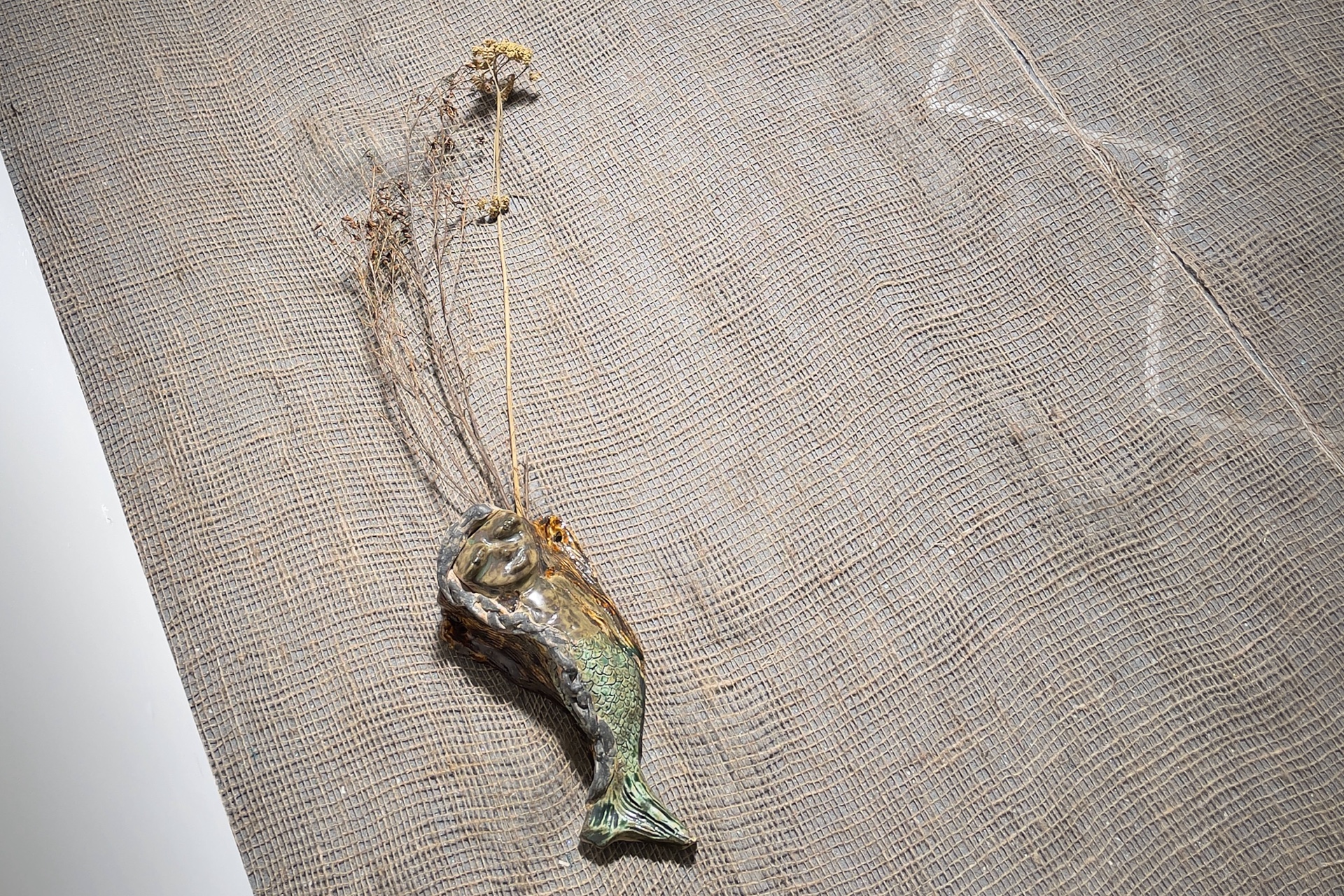 glazed ceramic mermaid with flowers on hessian